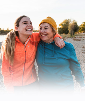 Dos mujeres sonríen y se ríen juntas junto al agua, disfrutando de un momento alegre y divertido.