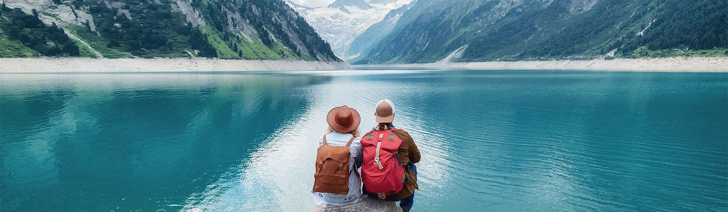 Dos personas sentadas frente a un lago.