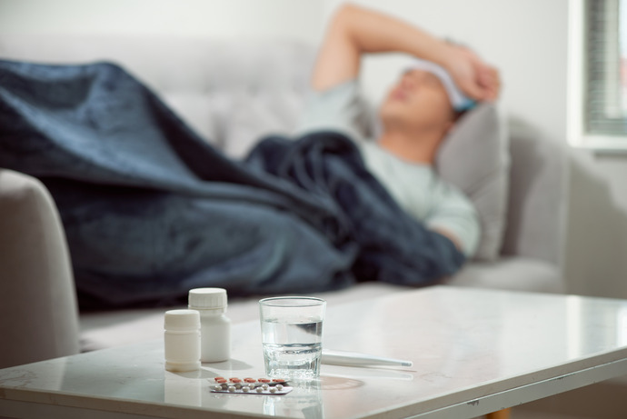 Hombre enfermo tumbado en el sofá con medicinas en la mesa