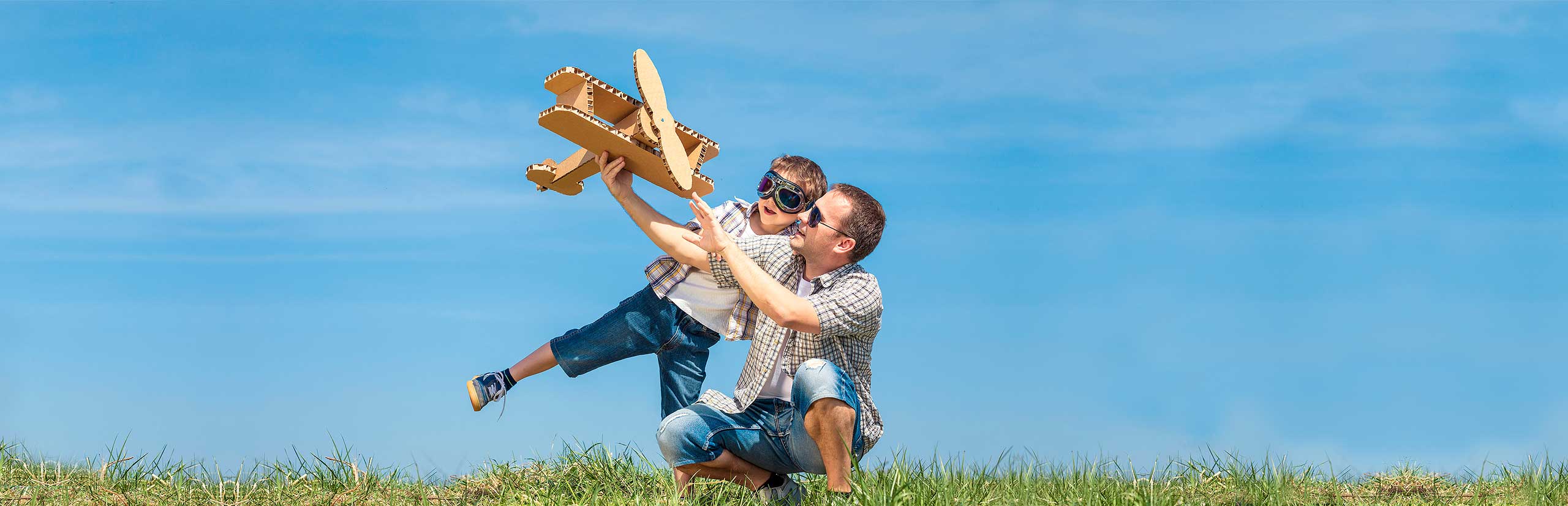 Papá e hijo juegan a ser aviadores con un aeroplano de cartón