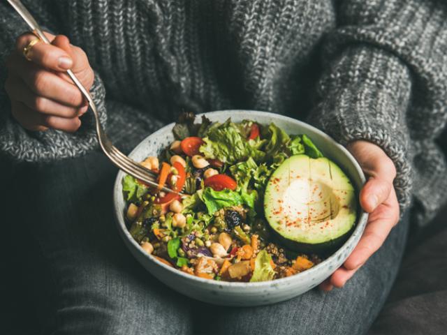 Mujer sujetando plato de ensalada con aguacate y verdura