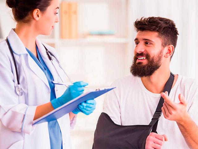 Hombre consultando al médico con un brazo enyesado.